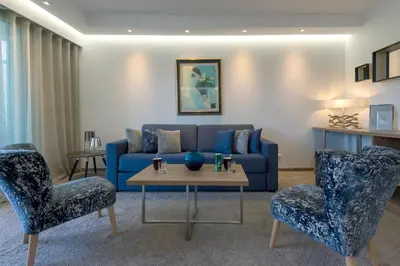 a living room with a blue couch and two chairs at Servotel Saint-Vincent in Nice