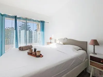 a bedroom with a large white bed with a window at Apartment Le Clos tranquille by Interhome in Nice