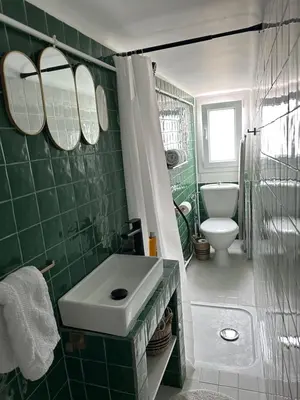 a green tiled bathroom with a sink and a toilet at Mansarde à 1 min de la mer in Nice