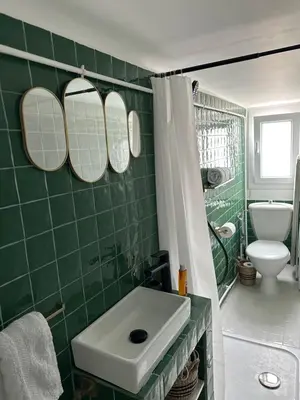 a green tiled bathroom with a sink and mirrors at Mansarde à 1 min de la mer in Nice