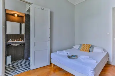 a white bedroom with a bed and a bathroom at Maison Bianchi - 24 Paul Deroulede in Nice