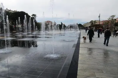 a fountain in a city with a person walking a dog at Résidence Aston la Scala in Nice