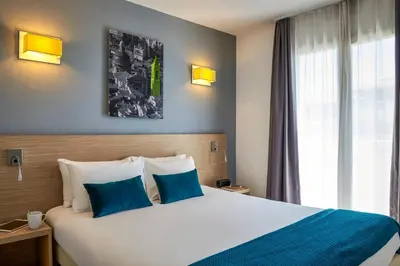a hotel room with a large bed with blue pillows at Aparthotel Adagio Access Nice Magnan in Nice