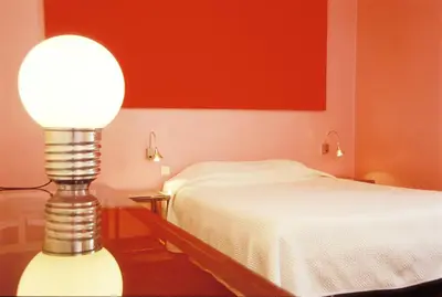 a bedroom with a bed and a lamp on a table at Le Windsor, Jungle Art Hotel in Nice
