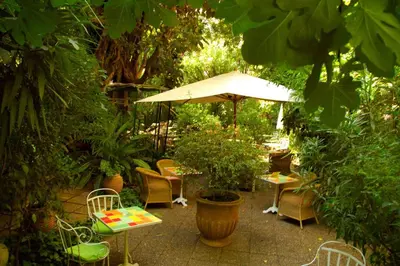 a patio with chairs and tables and an umbrella at Le Windsor, Jungle Art Hotel in Nice