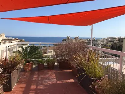 a balcony with plants and a red umbrella at LOFT 360° Nice in Nice