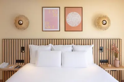a bedroom with a white bed with three pictures on the wall at Nice Centre Hotel in Nice