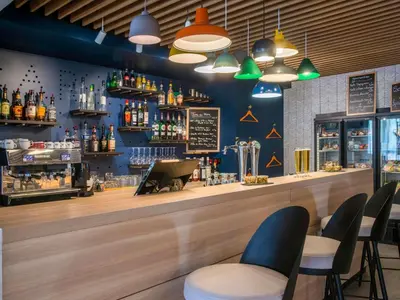a restaurant with tables and chairs and a bar at ibis Styles Nice Cap 3000 Aéroport in Saint-Laurent-du-Var