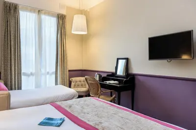 a hotel room with two beds and a desk with a television at Villa Otero by Happyculture in Nice