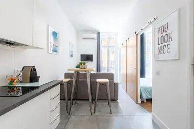 a kitchen with white cabinets and a table and chairs at 1 CASSINI - Magnifique 2 pièces place Garibaldi - Balcon in Nice