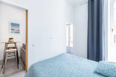 a bedroom with a bed and a table with a stool at 1 CASSINI - Magnifique 2 pièces place Garibaldi - Balcon in Nice