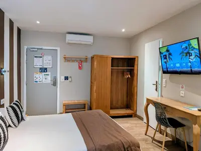 a bedroom with a bed and a desk and a television at H33 Hôtel in Nice
