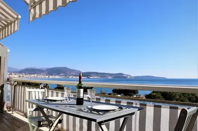 a table with a bottle of wine on a balcony with the ocean at 2P NEUF vue Promenade des Anglais / Tram 10min centre in Nice