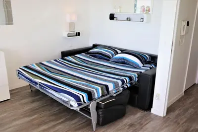 a bed with a striped blanket on it in a room at 2P NEUF vue Promenade des Anglais / Tram 10min centre in Nice