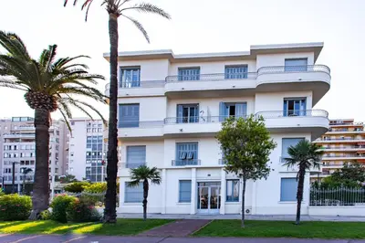 a white building with palm trees in front of it at #23 Henry IV Vue Panoramique Mer AC & Bright in Nice