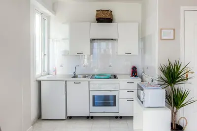 a white kitchen with white cabinets and a sink at #23 Henry IV Vue Panoramique Mer AC & Bright in Nice