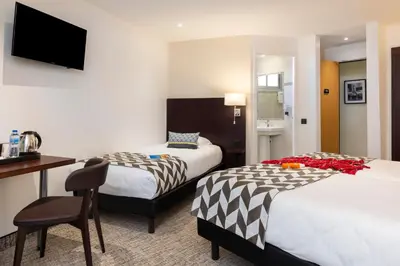 a hotel room with two beds and a desk at Hôtel Locarno Nice in Nice