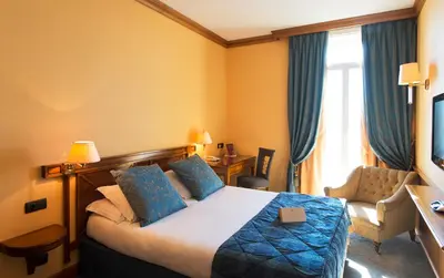 a hotel room with a bed and a chair at Hôtel West End Promenade in Nice
