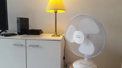 a white fan sitting on a desk next to a lamp at Nice Centre Studio Proche Mer in Nice