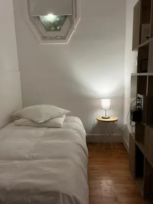 a bedroom with a bed and a table with a lamp at Nice Grand appartement face jardin in Nice
