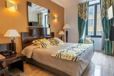 a bedroom with a large bed and a mirror at Hotel Le Meurice in Nice