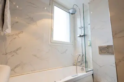 a bathroom with a shower and a tub and a window at Hotel Le Meurice in Nice