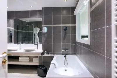 a bathroom with a tub and two sinks and a mirror at Hotel Aston La Scala in Nice