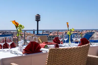 a table with red napkins and wine glasses on a balcony at Hotel Aston La Scala in Nice