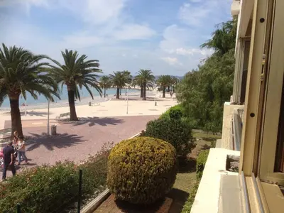 a view of a beach with palm trees and a building at MAEVA in Saint-Laurent-du-Var