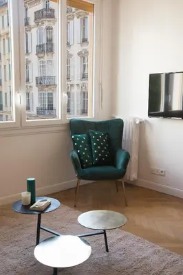 a living room with a green chair and two tables at Beautiful apartment in the heart of Nice in Nice