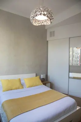 a bedroom with a bed with yellow pillows and a chandelier at Beautiful apartment in the heart of Nice in Nice