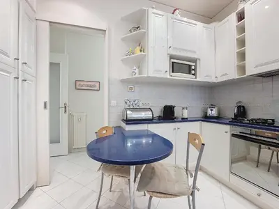 a kitchen with white cabinets and a blue table and chairs at Nestor&Jeeves - HORIZON PROMENADE - Central - Sea front in Nice