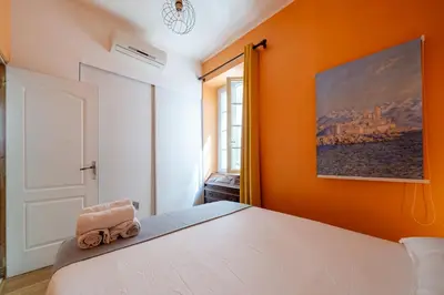 a bedroom with a white bed with an orange wall at Apartment Claudia - Central -Quiet- Near the Sea- AC- Private Parking in Nice