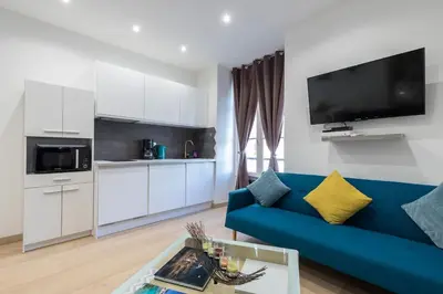 a living room with a blue couch and a kitchen at Historical Apartment Hyper Center in Nice