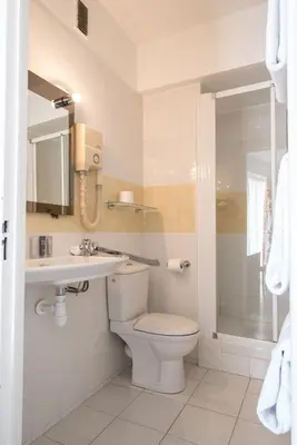 a bathroom with a toilet and a sink and a shower at Hôtel Comté de Nice in Beaulieu-sur-Mer