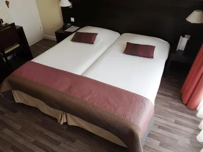 a large bed with two pillows on top of it at Hôtel Comté de Nice in Beaulieu-sur-Mer