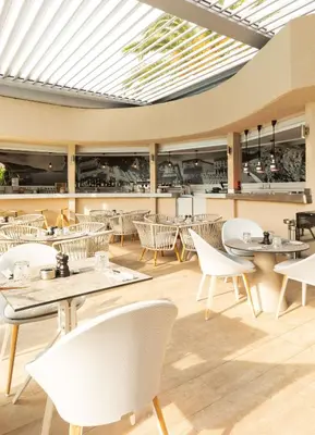 a restaurant with white chairs and tables and a ceiling at Radisson Hotel Nice Airport in Nice