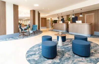 a lobby with blue stools and a table and chairs at Radisson Hotel Nice Airport in Nice