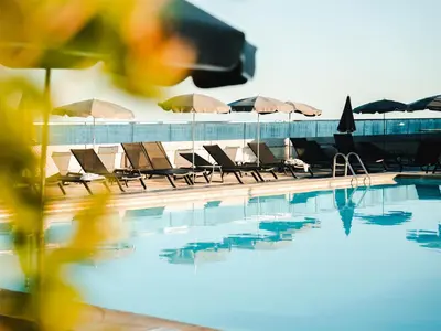 a group of chairs and umbrellas next to a swimming pool at Radisson Blu Hotel Nice in Nice