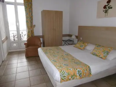 a bedroom with a bed and a chair and a window at Hôtel La Flore in Villefranche-sur-Mer