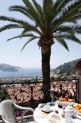 a table with food and a palm tree on a balcony at Hôtel La Flore in Villefranche-sur-Mer