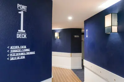 a room with a blue wall with a sign on it at The Deck Hotel by Happyculture in Nice