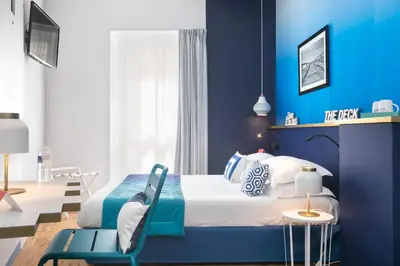 a blue bedroom with a bed and a chair at The Deck Hotel by Happyculture in Nice