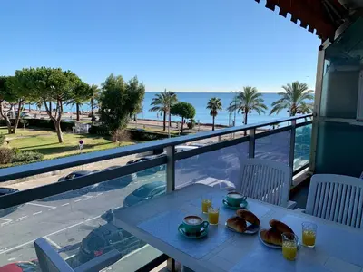 a table with plates of food on a balcony with the ocean at Studio F1 vue mer a 30m des plages in Cagnes-sur-Mer