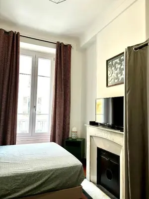 a bedroom with a bed and a fireplace with a television at GARE 5 minutes GARIBALDI RÉPUBLIQUE chambre PRIVEE non FUMEUR pour voyageurs CALMES TRAM au pied de l'immeuble in Nice