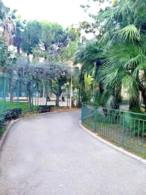 a walkway in a park with a fence and trees at Le Palladium quartier Tzaréwitch Nice in Nice