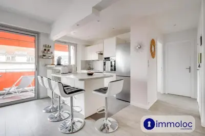 a white kitchen with a counter and chairs in it at Air-conditioned apartment in the Libération district in Nice