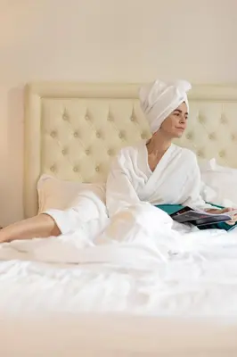 a woman laying in bed reading a book at Hôtel Nice Azur Riviera in Nice