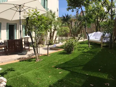 a lawn with an umbrella and a chair in a yard at Le jardin du port in Nice