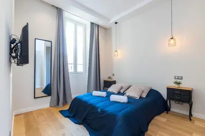 a bedroom with a bed with blue sheets and a mirror at Brand New 1 Bdr Place du Pin in Nice